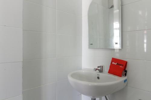 a white bathroom with a sink and a red book at RedDoorz Syariah near Universitas Negeri Padang in Padang
