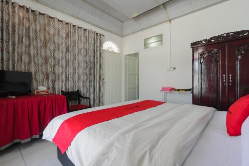 Un dormitorio con una cama roja y blanca y una mesa en RedDoorz Syariah near Universitas Negeri Padang en Padang