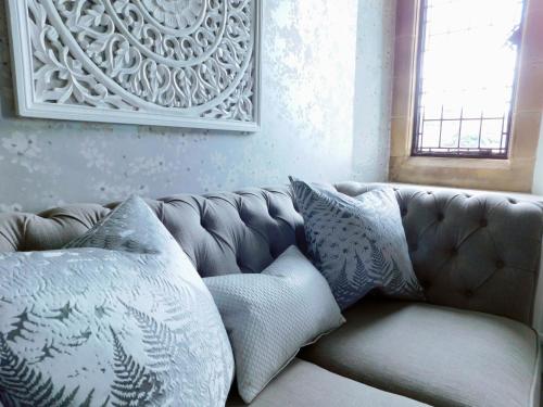 a couch with pillows sitting in a living room at Fischers Baslow Hall - Chatsworth in Baslow