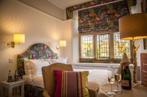 Fischers Baslow Hall - Chatsworth في باسلو: غرفة نوم مع سرير وطاولة مع أكواب من النبيذ