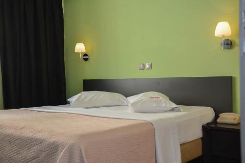 a bed with two white pillows and a green wall at Scorpios Sea Side Hotel in Piraeus