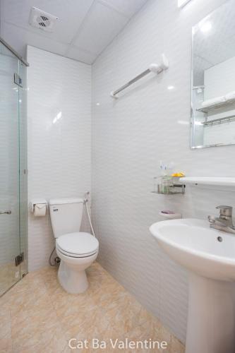 a white bathroom with a toilet and a sink at Cat Ba Valentine in Cat Ba