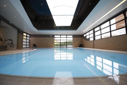 a swimming pool in a building with windows at Hôtel Restaurant Les Alizés in Lipsheim