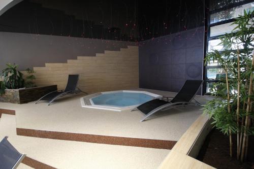 a swimming pool with two chairs and a hot tub at Hôtel Restaurant Les Alizés in Lipsheim