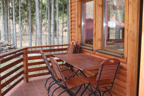 einen Holztisch und Stühle auf der Veranda einer Hütte in der Unterkunft Holiday Guest House in Odorheiu Secuiesc