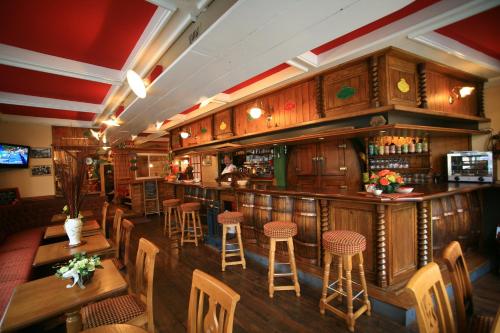 eine Bar in einem Restaurant mit Holztischen und Hockern in der Unterkunft Le Commerce in La Haye-du-Puits