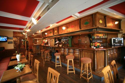 a bar in a restaurant with wooden tables and stools at Le Commerce in La Haye-du-Puits