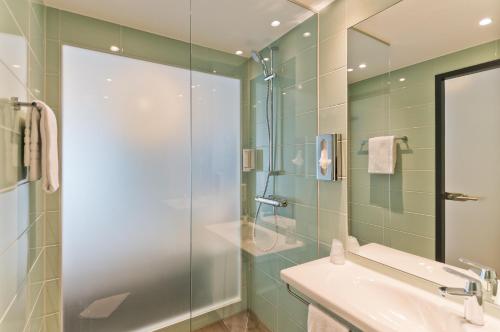 a bathroom with a glass shower and a sink at Super 8 by Wyndham Oberhausen am Centro in Oberhausen