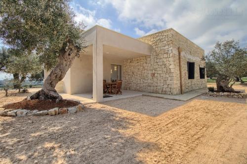 a stone house with a tree in front of it at Piccante Seaview by LoveSud in Patù