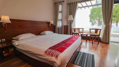 a bedroom with a large bed and a large window at Taman Simalem Resort in Tongging