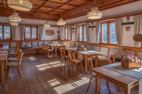 ein Restaurant mit Holztischen, Stühlen und Fenstern in der Unterkunft Hotel Restaurant Alatsee in Füssen