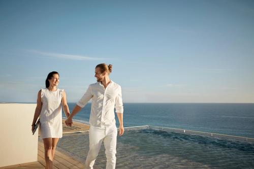 a man and a woman walking on a balcony overlooking the ocean at ROBINSON JANDIA PLAYA - Adults only in Morro del Jable