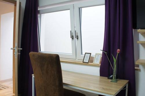 una scrivania con una sedia di fronte a due finestre di Einzelnwohnung mit eigenem Eingang a Weingarten