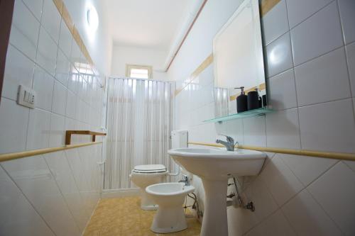 a white bathroom with a sink and a toilet at Experience Il Paesino in Licodia Eubea
