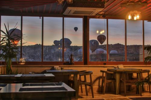 a restaurant with tables and windows with a view of balloons at Caravanserai Inn Hotel in Goreme
