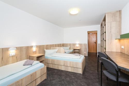 a room with two beds and a table and chairs at Sportpark Rabenberg in Breitenbrunn