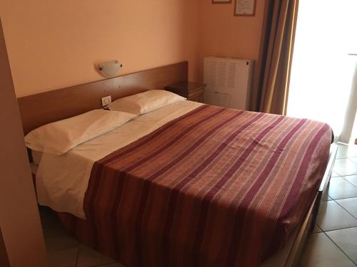a bedroom with a bed with a striped blanket on it at Hotel Il Pino in Garlasco