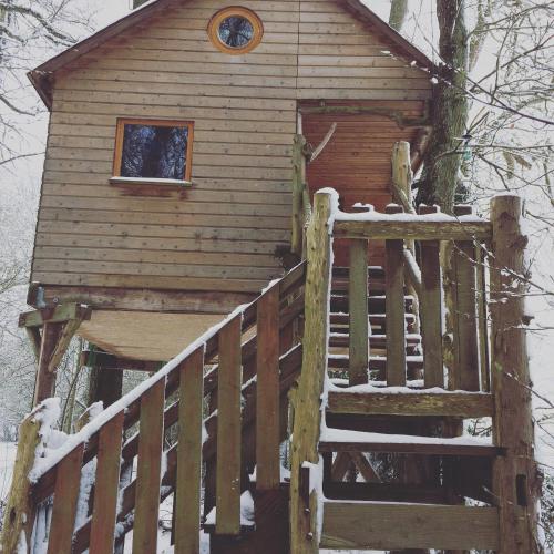 a wooden cabin with a staircase in the snow at La Cabane aux Secrets - Au Milieu de Nulle Part in Outines