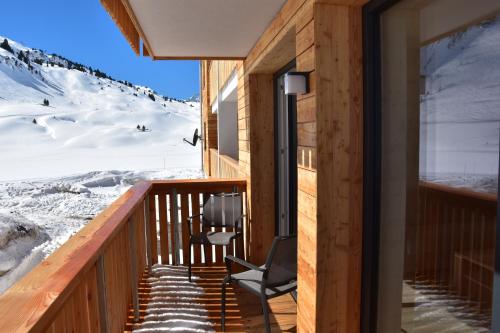 a room with a chair on a balcony with a snowy mountain at apart-wolf-arlberg in Warth am Arlberg