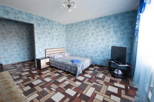 a bedroom with blue walls and a bed and a tv at Apartments BastiON in Kyzyl