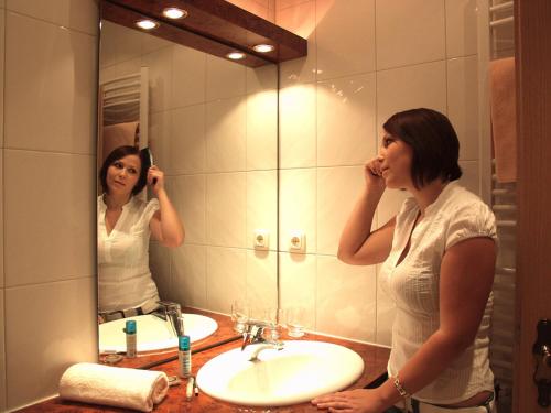 a woman standing in front of a bathroom mirror at Gasthof-Hotel Dilger in Rattenberg