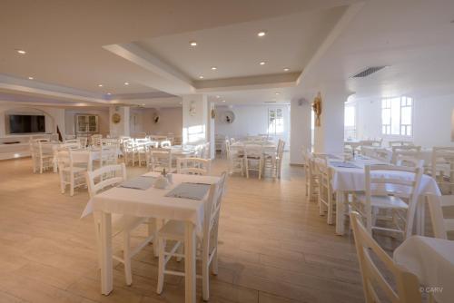 una sala da pranzo con tavoli bianchi e sedie bianche di Aspalathras White Hotel a Chora Folegandros