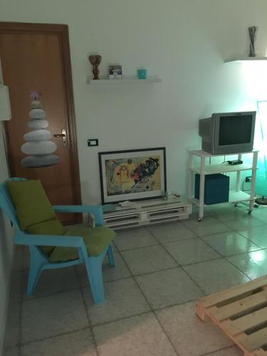a living room with a chair and a television at San Vito Lo Capo Via Savoia 250 Casa vacanze in San Vito lo Capo