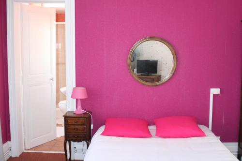 a bedroom with pink walls and a bed with two red pillows at Hôtel La Villa Lorraine in Toul