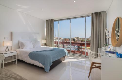 a bedroom with a bed and a large window at Estúdios Marina in Vilamoura