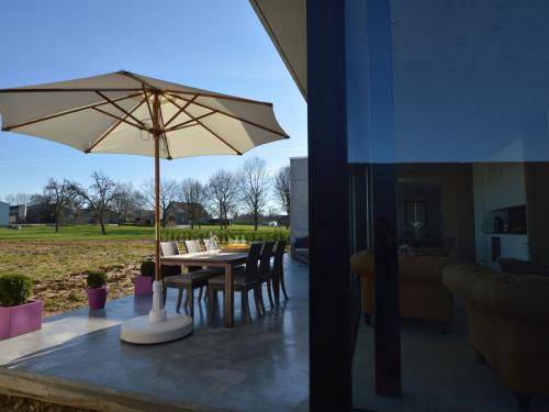 a patio with a table with an umbrella and chairs at Modern Dalhem Villa with Views in Dalhem