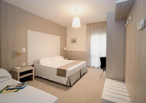 リド・ディ・イエゾロにあるHotel Atlanticoのベッドとデスクが備わるホテルルームです。