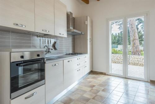 a kitchen with white cabinets and a large window at Dimora Villa Ada in Chiaramonte Gulfi