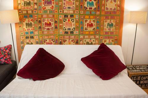a white bed with two red pillows on it at #FLH - Ethnic Flat, St Dimitrios in Thessaloniki
