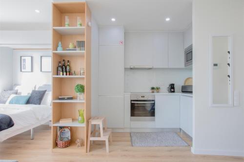 a room with a bed and a kitchen with white cabinets at Liiiving in Porto I Bright Light Studio in Porto