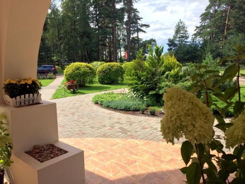 a garden with a brick walkway with bushes and trees at Guest House Karle in Vitrupe