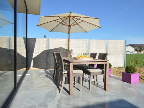 a wooden table with chairs and an umbrella on a patio at Modern Dalhem Villa with Views in Dalhem