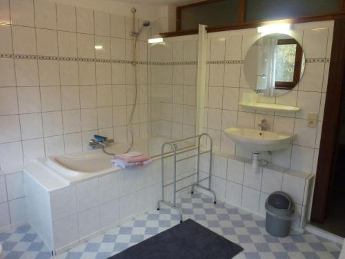 a white tiled bathroom with a sink and a tub and a mirror at Peaceful Nature Stay in Bohon in Barvaux