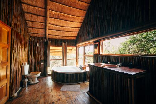 ein großes Bad mit einer Badewanne und einem WC in der Unterkunft Pezulu Tree House Lodge in Hoedspruit