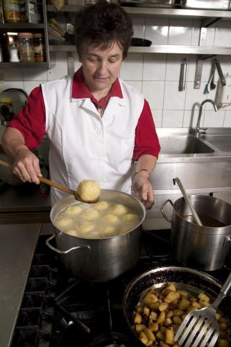 a woman cooking food in a pot on a stove at Bauer & Wirt Langthaler in Emmersdorf an der Donau