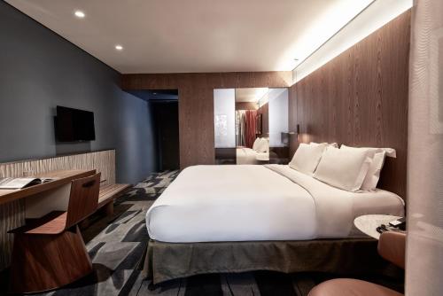 a bedroom with a large white bed and a desk at AthensWas Design Hotel in Athens