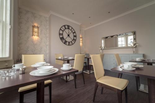 een eetkamer met een tafel en stoelen en een klok bij Anabelle's Guest House in Bath