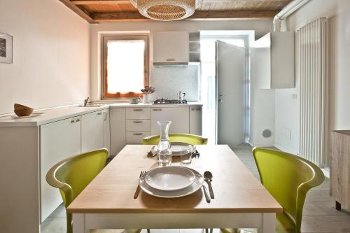 eine Küche mit einem Holztisch und grünen Stühlen in der Unterkunft CaseOspitali - CASA CARAMELLI bilocale in corte storica in Cernusco sul Naviglio