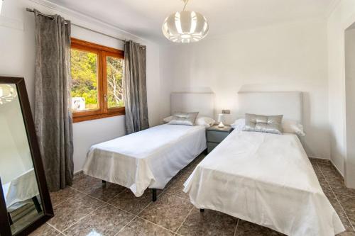 two beds in a room with a window at Villa Romaní in Sa Pobla