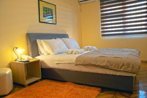 een slaapkamer met een bed met een nachtkastje en een raam bij Cicki Apartments I in Podgorica