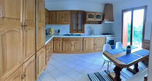 a kitchen with wooden cabinets and a table and a dining room at Apartment Blue Bay in Malinska