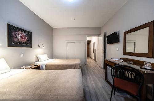 a hotel room with two beds and a desk and a mirror at Vergina Hotel in Thessaloniki