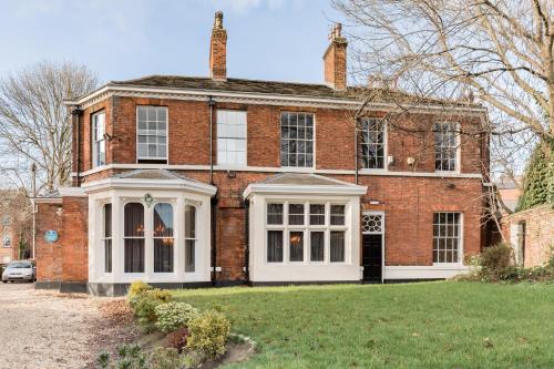 an old brick house with a white front porch at The Heaton at Claremont Serviced Apartments in Leeds
