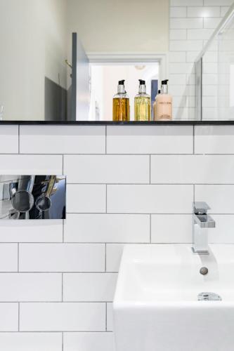 a white bathroom with a sink and a mirror at The Heaton at Claremont Serviced Apartments in Leeds