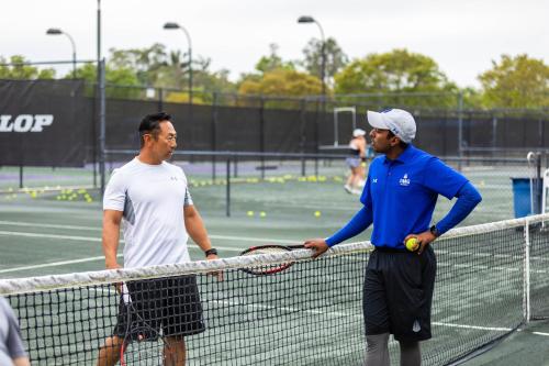two men shaking hands over the net on a tennis court at Legacy Hotel at IMG Academy in Bradenton