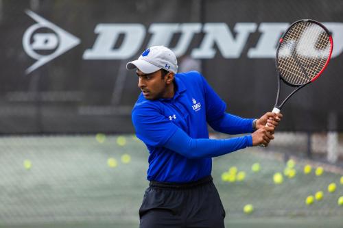 a man holding a tennis racket on a court at Legacy Hotel at IMG Academy in Bradenton
